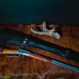 A handmade leather rifle scabbard and a knife on a table.