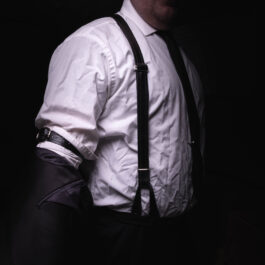 A man wearing leather dress suspenders.