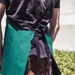a man wearing a green Canvas Apron and a black shirt.