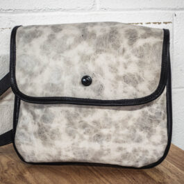 An Ivory Leather Satchel sitting on top of a wooden table.