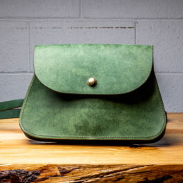 A Green Leather bag on a wooden Table