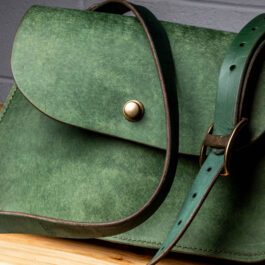 A Green Leather bag on a wooden Table
