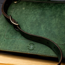 A Green Leather bag on a wooden Table