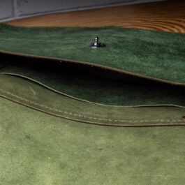 A Green Leather bag on a wooden Table