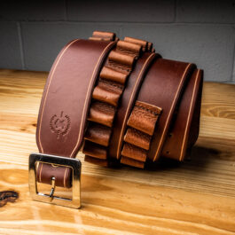 a light brown leather belt with bullet loops on a wooden table