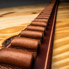 a light brown leather belt with bullet loops on a wooden table