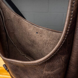 A gray leather bag on a wooden table