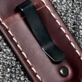 a black steel clip attached to a leather sheath