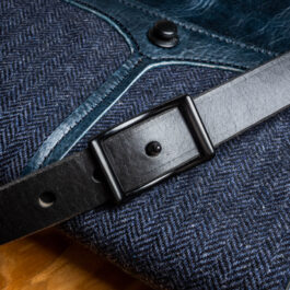 a blue leather bag with a black strap and black steel buckle
