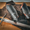 a pair of upper arm armor on a table next to a sword.