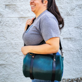 A woman carrying a Bison Leather Mini Duffel in green and black.