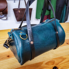 A Bison Leather Mini Duffel sitting on top of a wooden table.