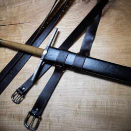 a Wood Core Scabbard for the Albion Meyer and a leather belt on a wooden table.