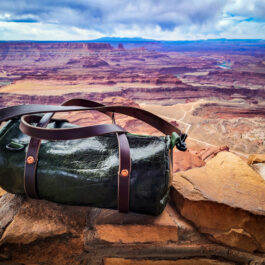 A Bison Leather Mini Duffel sitting on top of a rock.