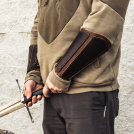 a pair of mercenary vambraces worn by a man with a sword