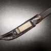 A knife with a custom leather sheath on a table.