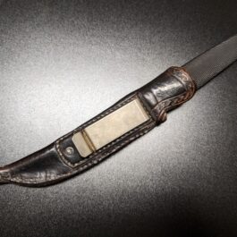 A knife with a custom leather sheath on a table.