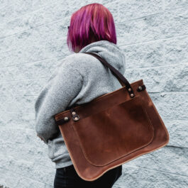 a woman holding the solvang tote in horween dublin english tan