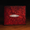 A metallic red rayskin wallet with a white eye on it.