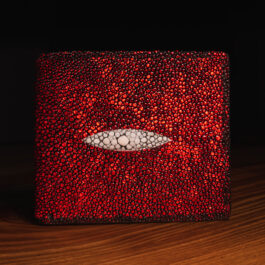 A metallic red rayskin wallet with a white eye on it.