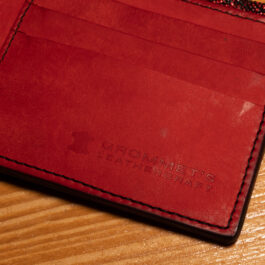 A Metallic Red Rayskin wallet sitting on top of a wooden table.