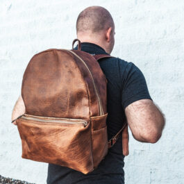 A man wearing a light brown leather backpack